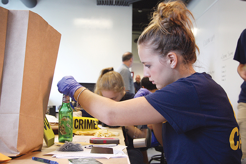 A Student examining mock crime scene evidence.