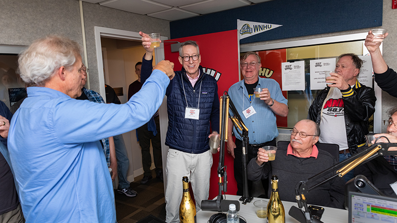 Bruce Barber (center) leads Chargers in a celebratory toast, helping to officially mark the 50th anniversary of WNHU.