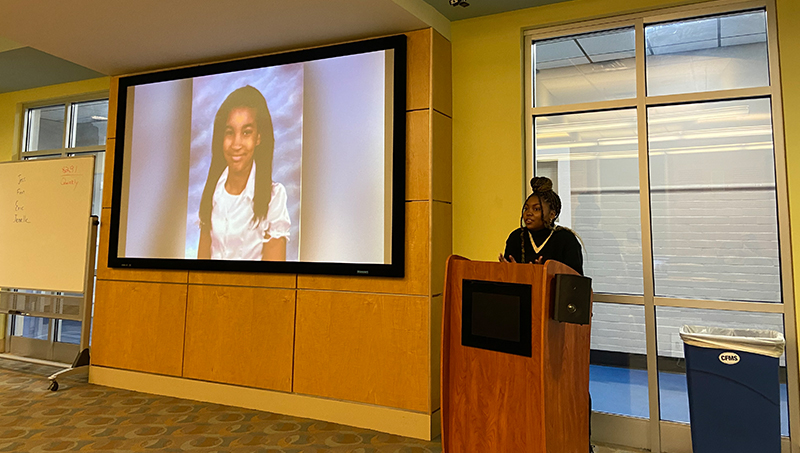 A student stands at a podium and is giving a presentation.