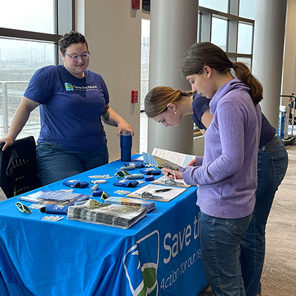 One student is tabling at an event answering questions.