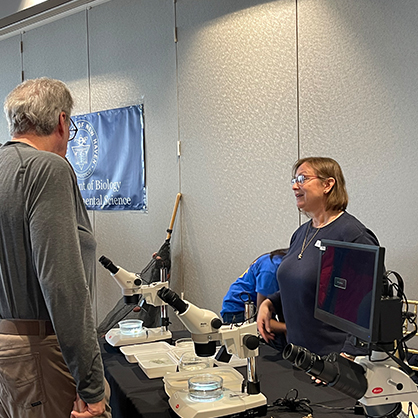 A professor standing behind a table at an event.