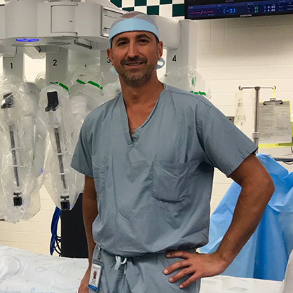 LaLonde, wearing scrubs, standing in front of medical machinery.