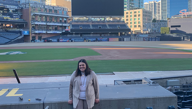 Tess Bloom poses in front of the hometeam dugout at Petco Park.