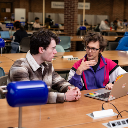 two students about academics in front of their computers