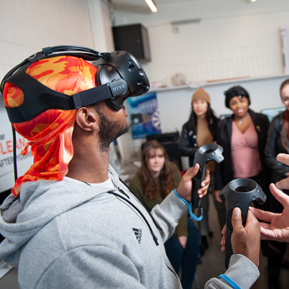 A man, wearing a VR headset, at a computer.