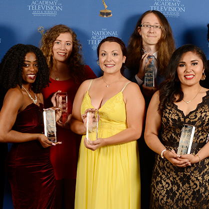 Five people posing together in front of a step and repeat.